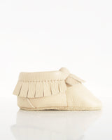 Moccasins – Lederschuh für Babys und Kleinkinder mit Fransen am oberen Bündchen in der Farbe helles creme in der Seitenansicht.