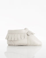 Moccasins – Lederschuh für Babys und Kleinkinder mit Fransen am oberen Bündchen in der Farbe weiß in der Seitenansicht.