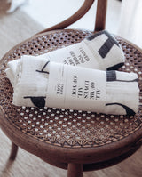 Zwei zusammengefaltete Musselintücher jeweils mit Banderolen liegen auf einem Stuhl.