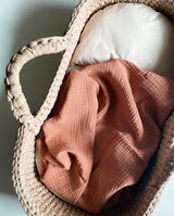 Musselindecke für Babys in terrakotta von UNIQUE LOVE liegt in einem Baby Körbchen.