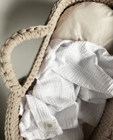 Musselindecke für Babys in weiß von UNIQUE LOVE liegt in einem Baby Körbchen.
