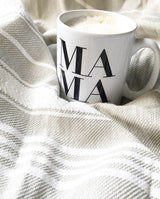 Die MAMA Keramik Henkeltasse mit einem Heißgetränk gefüllt steht auf einer Stoffunterlage.