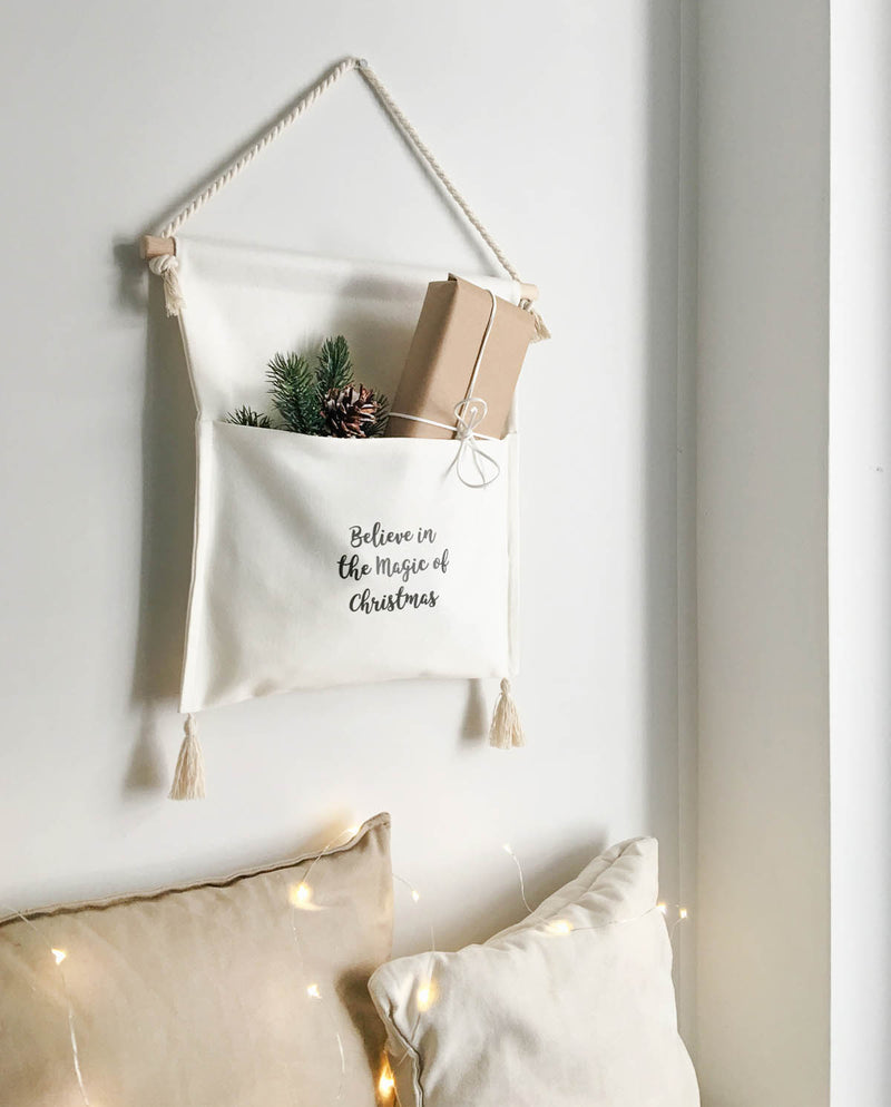 Adventskalender bestehend aus einer kleinen Tasche, die mit Geschenken befüllt wurde, hängt an der Wand.