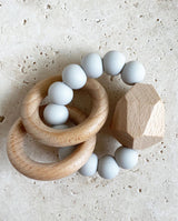 Greifling/Beißring für Babies aus hellgrauen Silikonperlen, zwei Holzringen und einem Holzstein.