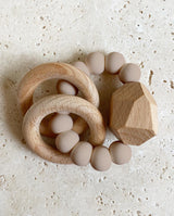 Greifling/Beißring für Babies aus Silikonperlen in der Farbe sand, zwei Holzringen und einem Holzstein.