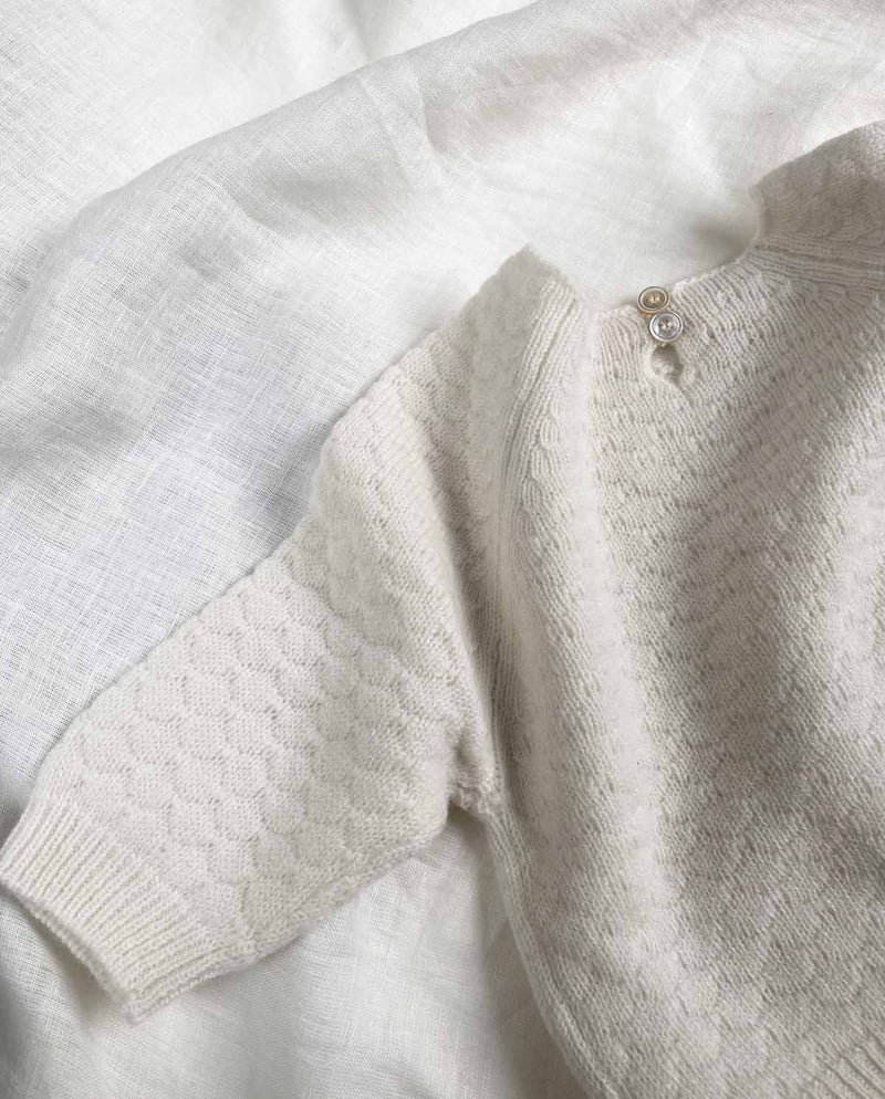 Detailansicht des Baby Cashmere Sweaters in creme mit kleiner Knopfleiste am oberen Büdchen.