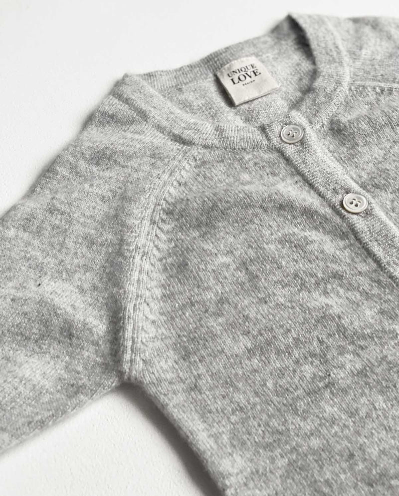 Detailansicht von grauem Baby Cashmere Overall in hellgrau und langen Ärmeln mit Knopfleiste.