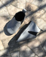 Chelsea Boots – Leder Lauflernschuhe für Kleinkinder in der Farbe hellgrau In Front- und Seitenansicht auf einem Steinboden.