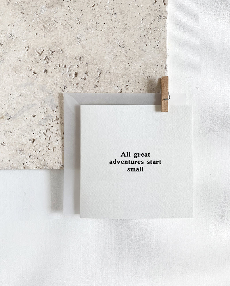 Quadratische Grußkarte zum Klappen mit milchigem Briefumschlag und Holzklemme. Spruch: "All great adventures start small"