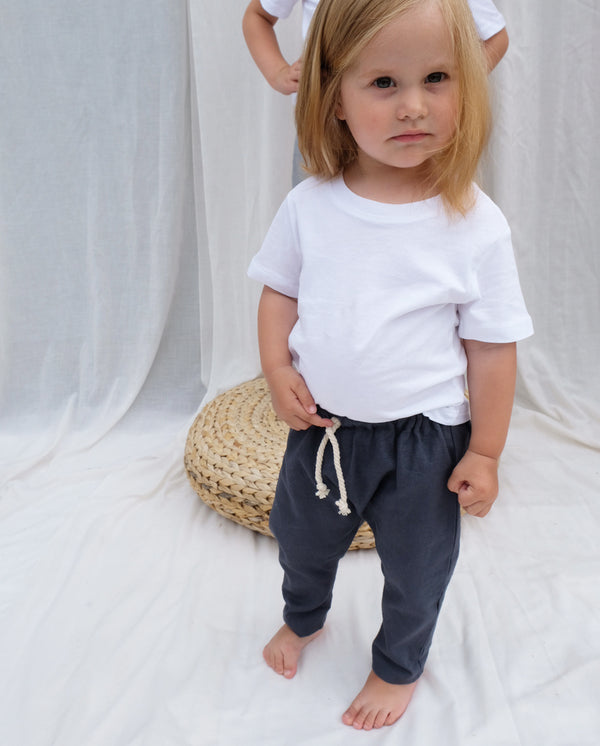 Ein Kleinkind trägt die Hose aus Leinen für Babys und Kleinkinder in der Farbe dunkelgrau.