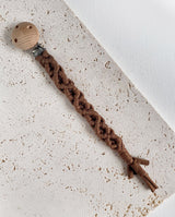 Schnullerband aus Stoff im Makramee Design mit Holzclip in der Farbe dunkelbraun.