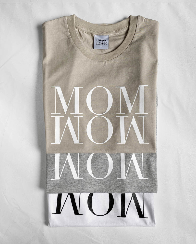 Drei übereinander gefaltete Statement T-Shirts mit der Aufschrift MOM WOW. Von oben nach unten: sand, grau und weiß.